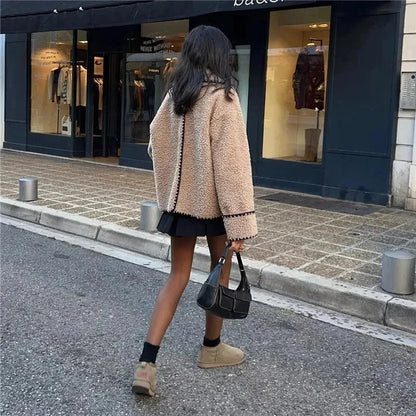 Veste teddy femme beige avec coutures noires, en matériau doux, coupe confortable.